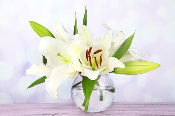 Piękne lilia w wazonie na stole na jasnym tle — Zdjęcie stockowe