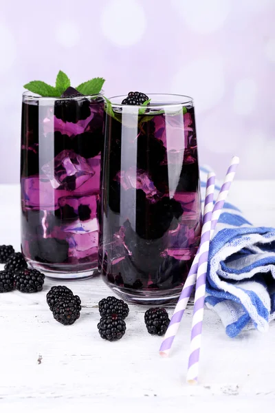 Tasty cool blackberry lemonade with ice on wooden table, on light background — Stock Photo, Image