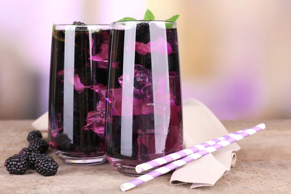 Tasty cool blackberry lemonade with ice on wooden table, on light background — Stock Photo, Image