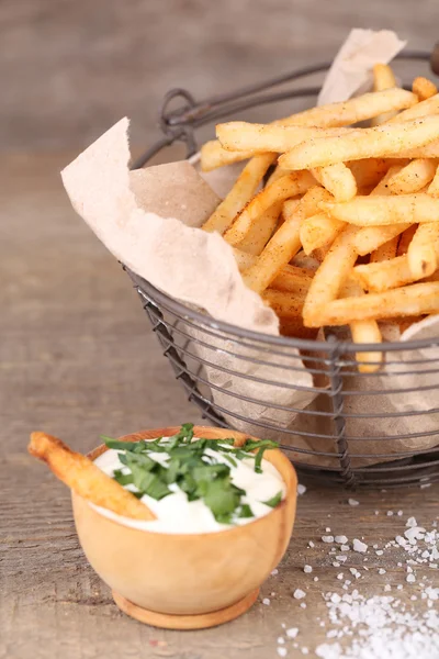 Tasty french fries in metal basket on wooden table — Stock Photo, Image