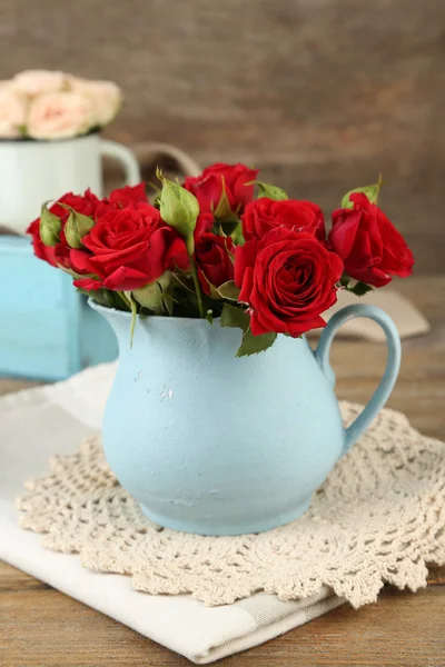 Ramo de rosas rojas en jarrón sobre fondo de madera —  Fotos de Stock