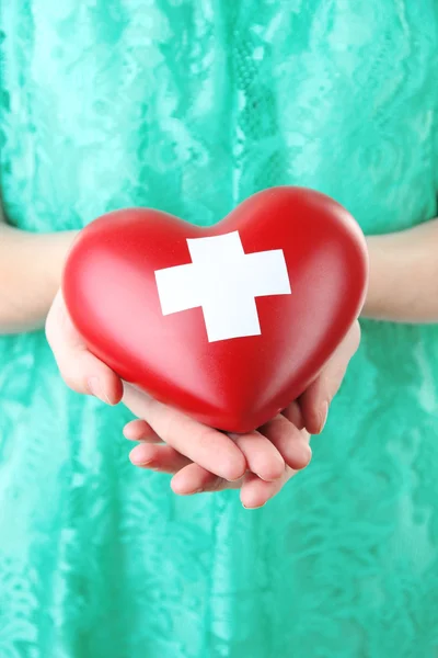 Coração vermelho com sinal de cruz na mão feminina, close-up , — Fotografia de Stock