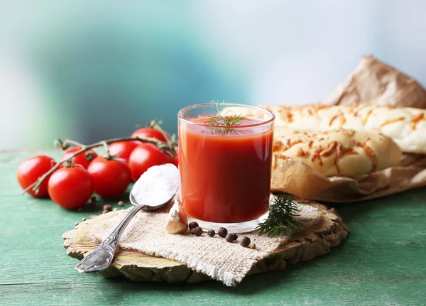 Домашній томатний сік у склянці, спеціях та свіжих помідорах на дерев'яному столі, на яскравому фоні — стокове фото
