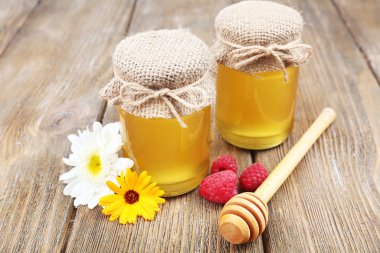 ahşap masa üzerinde kır çiçekleri ve lezzetli taze bal dolu kavanoz