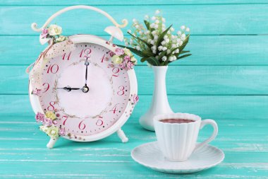 Çiçek ve mavi ahşap zemin üzerine çay ile güzel vintage çalar saat