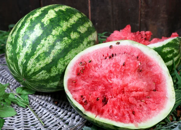 Reife Wassermelonen auf Korbblech auf Gras in der Nähe von Zaun — Stockfoto