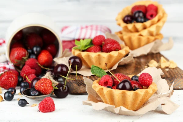 Tasty tartlets with berries on wooden table — Stock Photo, Image