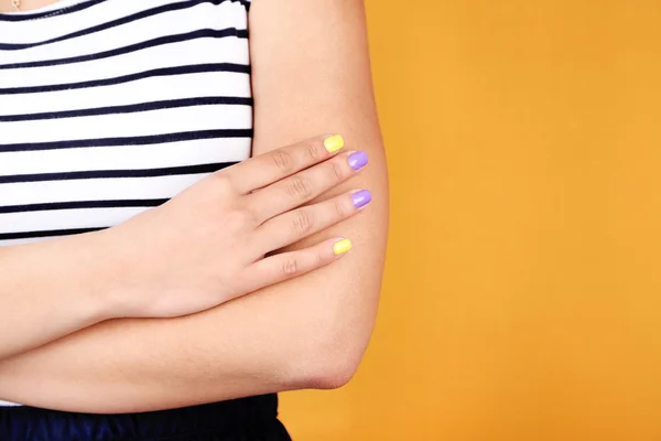 Mano femminile con unghie colorate alla moda, primo piano, su sfondo a colori — Foto Stock