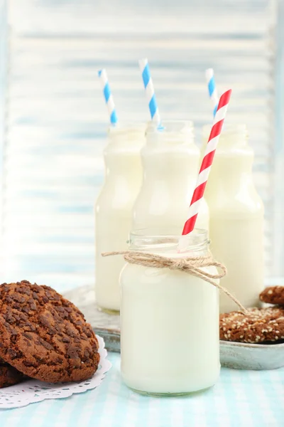 Leche en botellas con paja de papel sobre la mesa — Foto de Stock