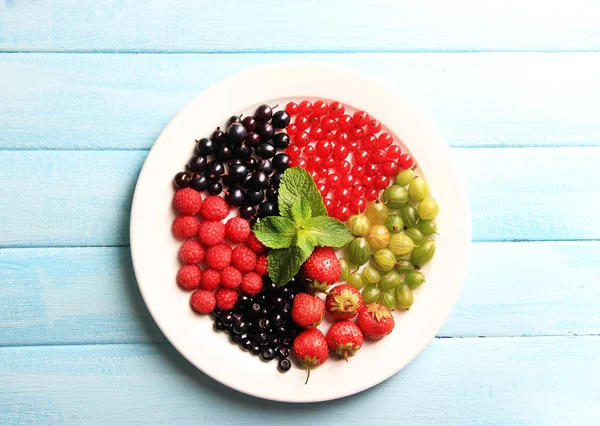 木製の背景の色に、皿の上の森林の果実 — ストック写真