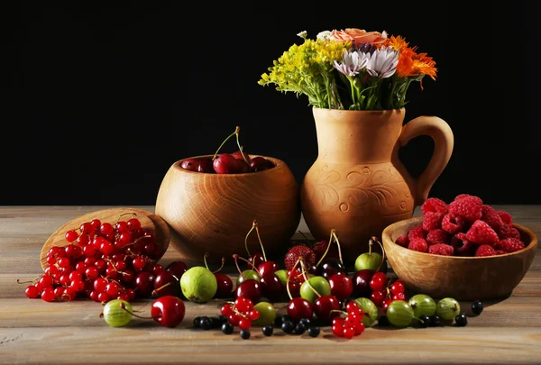 Stilleven met bessen en bloemen op donkere achtergrond — Stockfoto