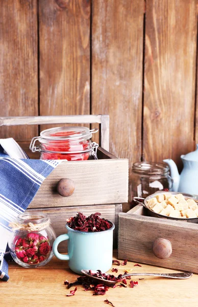 Dried hibiscus tea in color mug, brown sugar  in box on wooden background — Stock Photo, Image