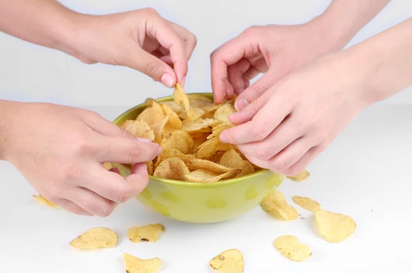 As mãos de pessoas tomam batatas fritas da tigela — Fotografia de Stock