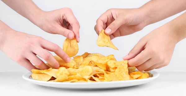 As mãos de pessoas tomam batatas fritas da tigela — Fotografia de Stock