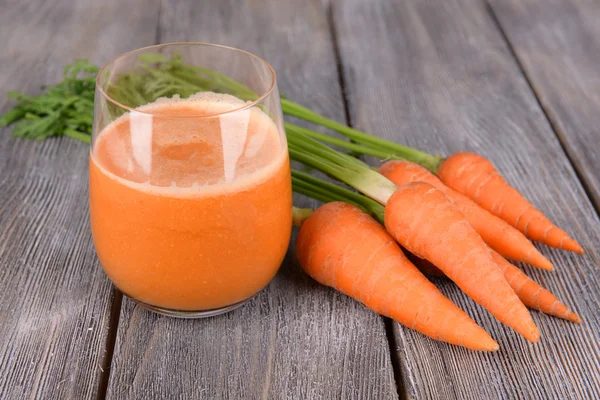 Bicchiere di succo di carota e carote fresche su sfondo di legno — Foto Stock