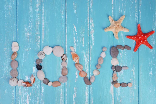 Palabra de amor hecha de conchas de mar y piedras sobre fondo de madera —  Fotos de Stock