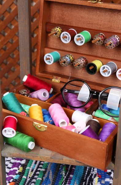 Colorful threads for needlework in wooden box on shelf in room — Stock Photo, Image