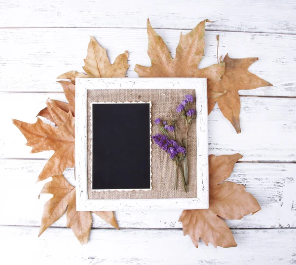 Holzrahmen mit getrockneten Blumen, Blättern und alten Blankofotos auf Holzgrund — Stockfoto