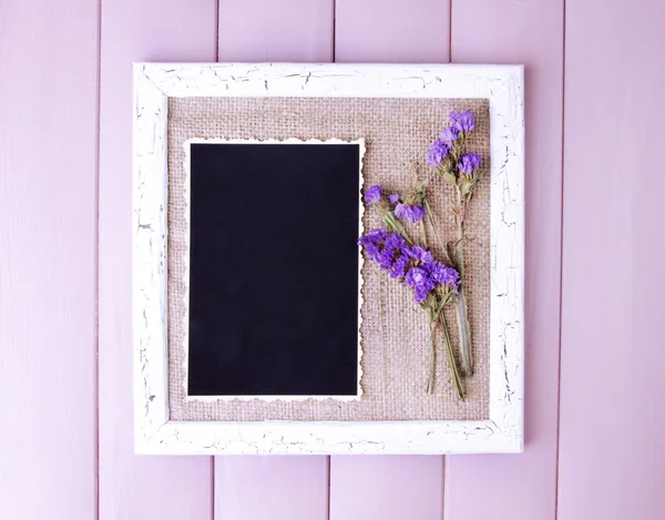 Holzrahmen mit getrockneten Blumen und alten Blankofotos auf Holzgrund — Stockfoto