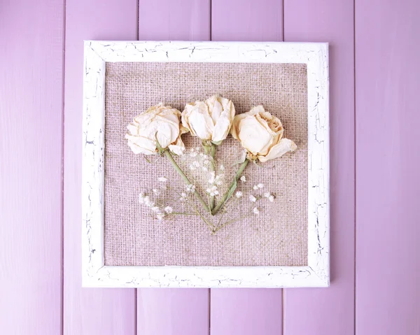 Holzrahmen mit getrockneten Blumen auf Holzgrund — Stockfoto