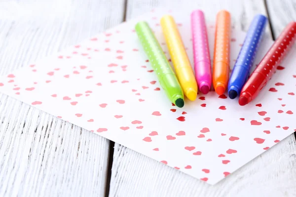 Bright markers with paper on wooden table close-up — Stock Photo, Image