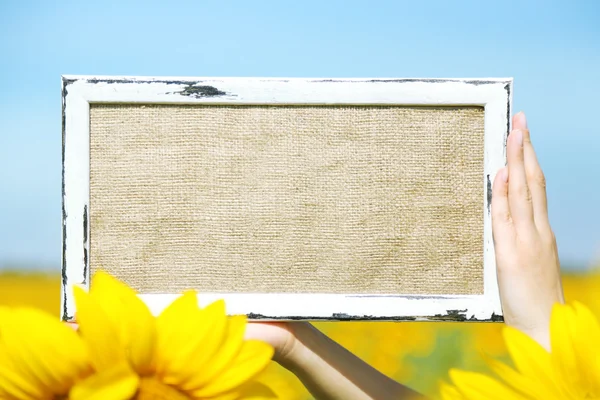 Blackboard blank in hands in sunflower field — Stock Photo, Image