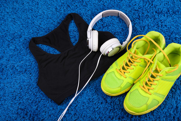 Sport clothes, shoes and headphones on color carpet background. 
