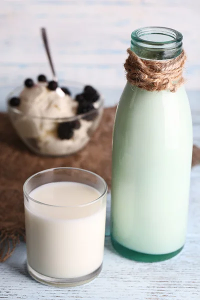 Skleněná láhev mléka a tvarohu na dřevěné pozadí — Stock fotografie