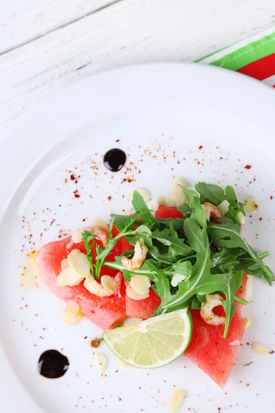 Sallad med vattenmelon, fetaost, ruccola, räkor, balsamisk sås på plattan, på trä bakgrund — Stockfoto