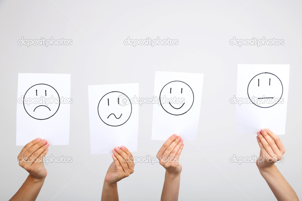 Hands holding up different smileys on grey background