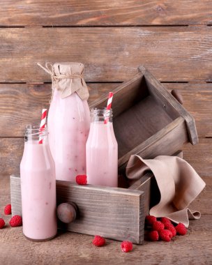 gri pembe ahşap zemin üzerine lezzetli frambuazlı smoothie içki şişeleri