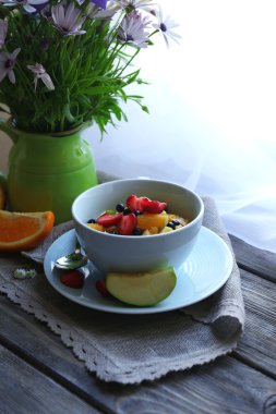 Yararlı ev yapımı meyve salatası ve masaya çiçek 