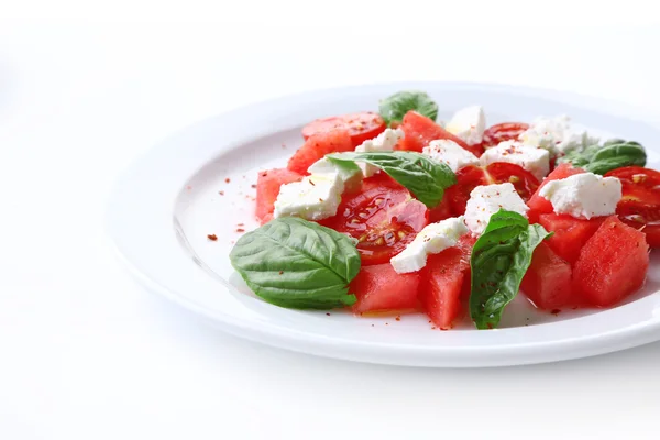 Sallad med vattenmelon, fetaost och basilika blad på plattan, isolerad på vit — Stockfoto