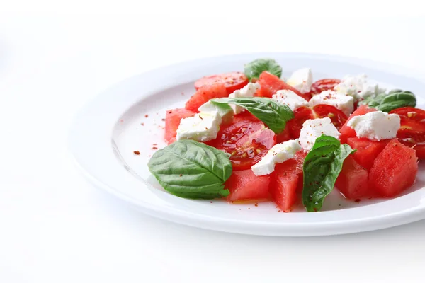 Salada com melancia, feta e manjericão folhas na placa, isolado em branco — Fotografia de Stock