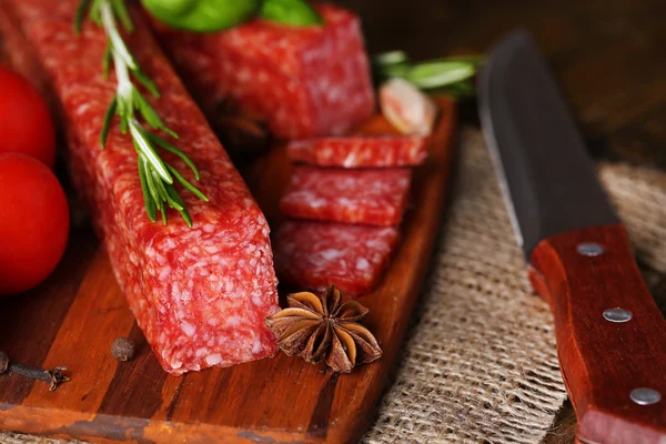 Sabrosa salchicha salami y especias sobre fondo de madera — Foto de Stock