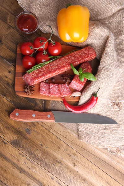 Salsicha de salame saboroso e especiarias em fundo de madeira — Fotografia de Stock
