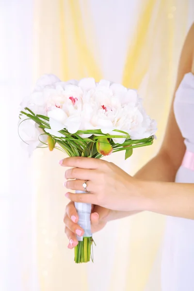 Bruid houden bruiloft boeket van witte pioenrozen, close-up, op lichte achtergrond — Stockfoto