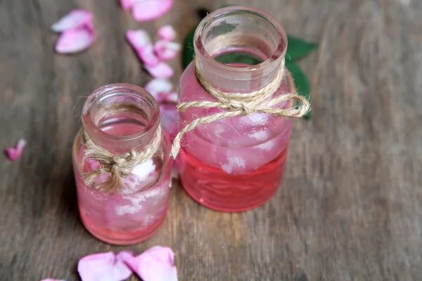 Huile de rose en bouteilles sur fond de bois couleur — Photo