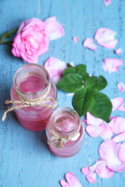 Rosenöl in Flaschen auf farbigem Holzhintergrund — Stockfoto