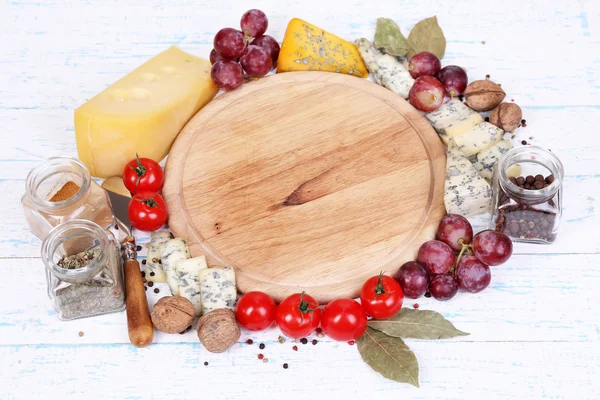Различные виды сыра с пустой доской на столе крупным планом — стоковое фото