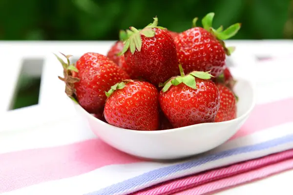Zralé sladké jahody v misce na stole v zahradě — Stock fotografie