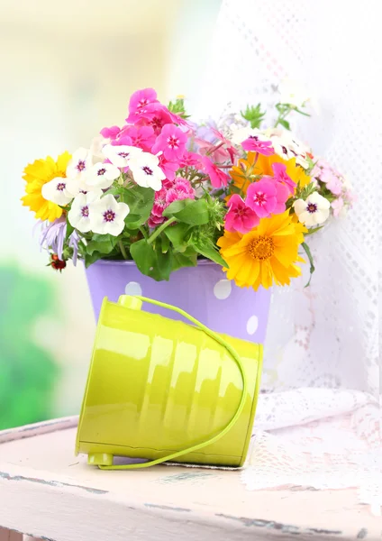 Strauß bunter Blumen im dekorativen Eimer, auf Stuhl, auf hellem Hintergrund — Stockfoto