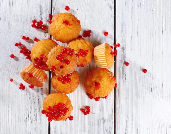 Muffin saboroso com bagas de groselha vermelha na cor de fundo de madeira — Fotografia de Stock