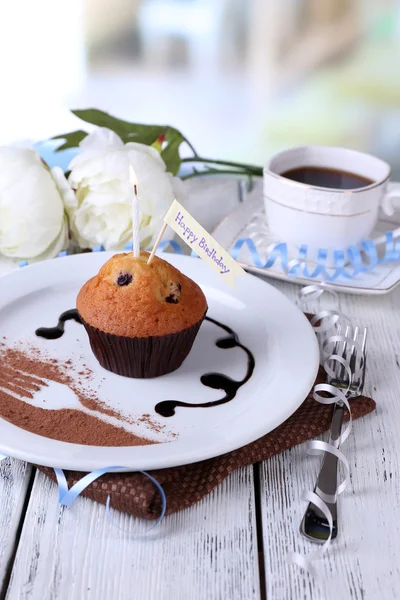 Черничный кекс с шоколадным соусом на тарелке, на деревянном столе, на ярком фоне — стоковое фото