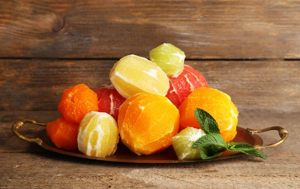 Citrus fruits without skin on tray, on wooden background — Stock Photo, Image