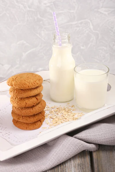 Mléko a soubory cookie v tabulce na světle šedém pozadí — Stock fotografie
