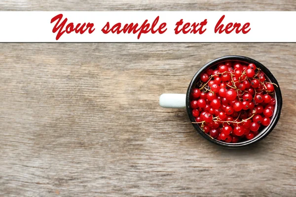 Red currant berries in mug on wooden background — Stock Photo, Image