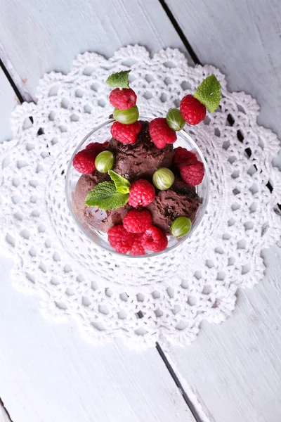 Schokoladeneis mit Minzblättern und reifen Beeren in Glasschale, auf farbigem Holzhintergrund — Stockfoto