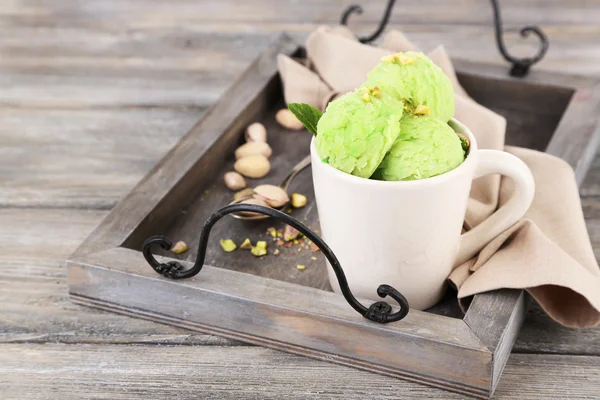 Tasty pistachio ice cream in cup on wooden table — Stock Photo, Image