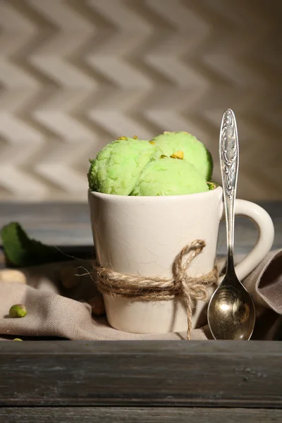 Tasty pistachio ice cream in cup on wooden table — Stock Photo, Image